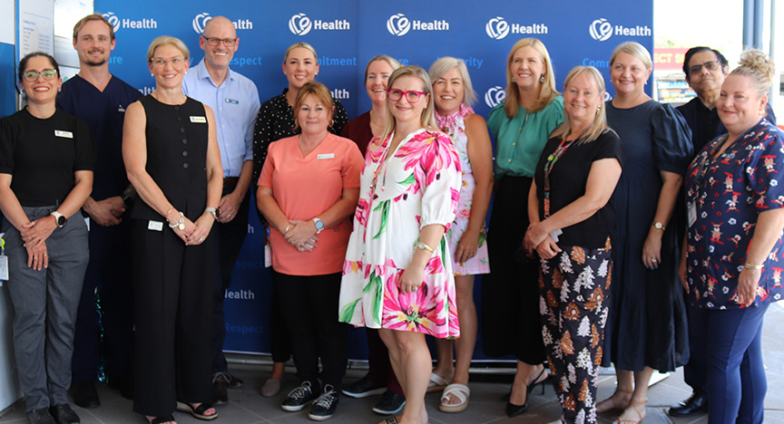A large group of health staff stand outside a nurse-led clinic to celebrate its first birthday.