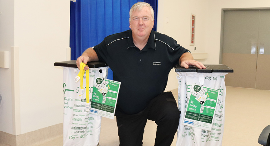 A hospital worker crouches next to collection bags for tourniquets, which are being diverted to recycling.