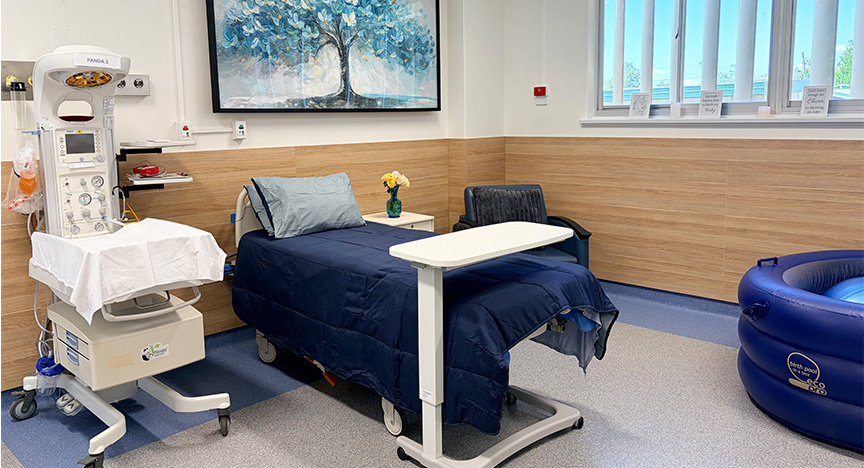 Biloela Hospital birth suite has been revamped ready for the introduction of birthing services late next month. A hospital birthing suite with a hospital bed, baby monitoring station and navy blue birthing pool, with a print of a tree on the wall.
