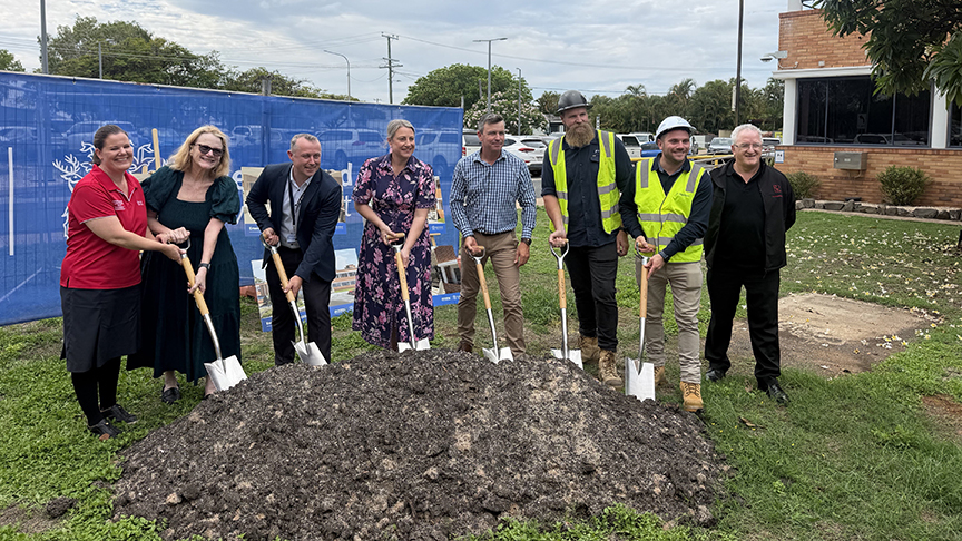 Group of smiling people holding shovels, in a pile of dirt, outside Emerald Hospital
