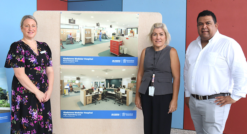 Central Queensland Health General Manager Gladstone and Banana Anita Pierantozzi, Central Queensland Health Chief Executive Lisa Blackler and Central Queensland Health Board Chair Matthew Cooke stand together smiling in front of two posters showing artist's concepts of the new Gladstone modular hospital.